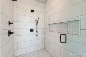 A bathroom with two showers and a glass door