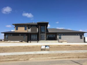 A large house with lots of windows and a lot of grass.