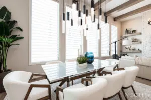 A dining room table with chairs and lights hanging from the ceiling.