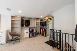 A room with many shelves and clothes hanging on the wall.