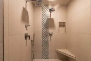 A bathroom with two shower heads and a bench.