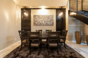 A dining room table with chairs and lights on the wall.