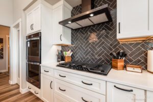 White kitchen with black tile backsplash.