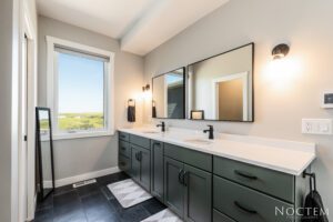 Modern bathroom with green cabinets and dual sinks.