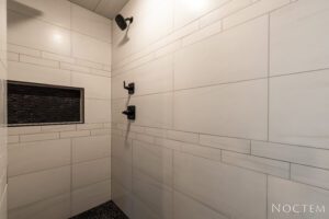 White tiled shower with black accents.