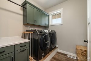 Laundry room with green cabinets and washer dryer.